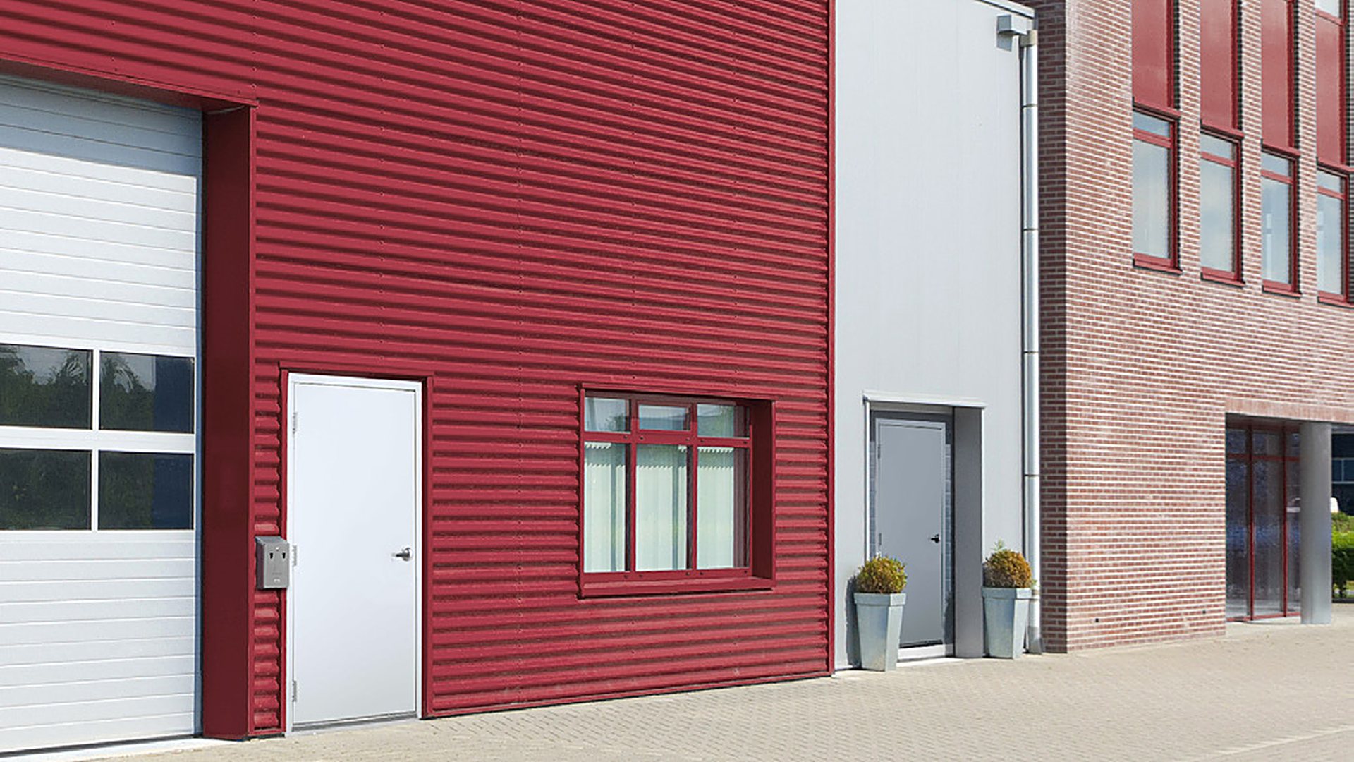 Steel walk doors and sectional door in a red clad industrial building